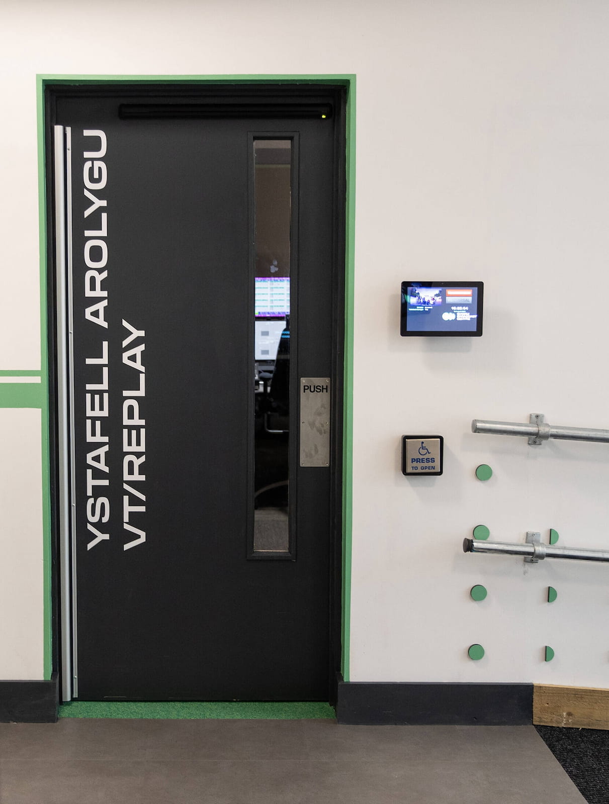 The VT/Replay room door with the disabled access button and room information screen next to it